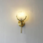 Clérachic compact Zavarara wall light lit on a plain wall, the alabaster shade glowing amber from within.