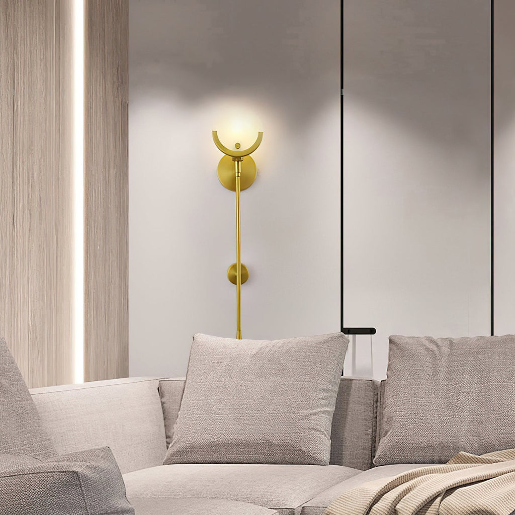 Clérachic tall sconce lit on a white wall above a pale linen sofa in a modern living room.