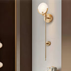 Clérachic three-quarter view of the tall sconce unlit on a pale stone wall in a dimly lit hallway.