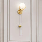 Clérachic tall Zavarara sconce lit on a cream panelled wall, seen at an angle with the opal shade aglow.