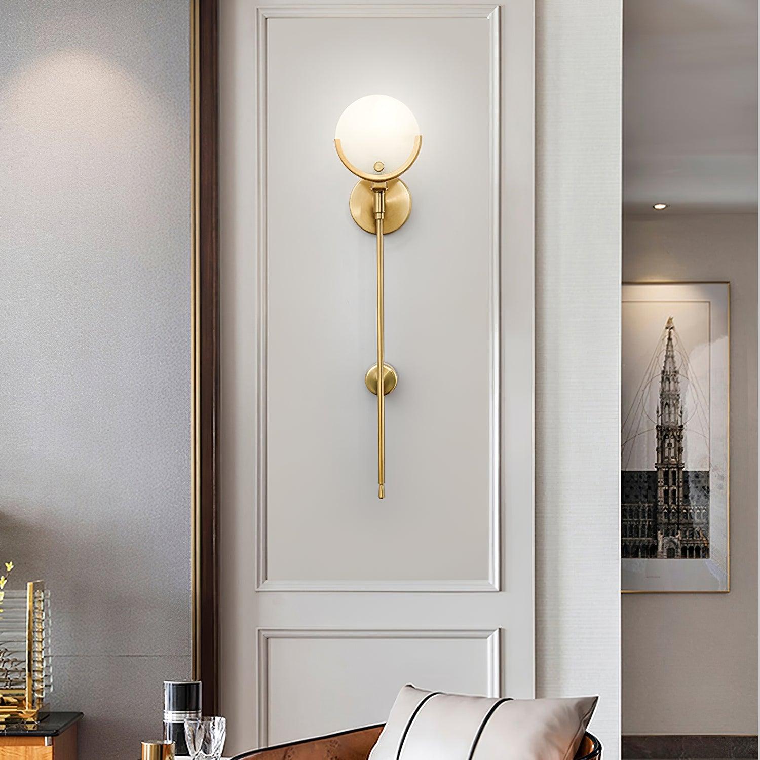 Clérachic tall Zavarara wall light lit on a cream panelled hallway wall, a framed print visible beyond.