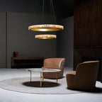 Two-tier brass alabaster chandelier lit above a marble coffee table and two blush lounge chairs.
