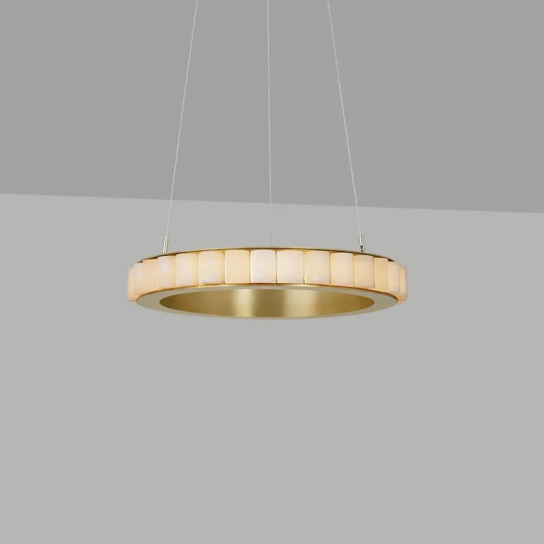 Brass alabaster chandelier switched on, stone tiles glowing warm against a grey studio backdrop.