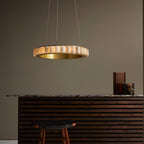 Brass alabaster chandelier lit above a slatted wood counter with a marble top and leather stool.