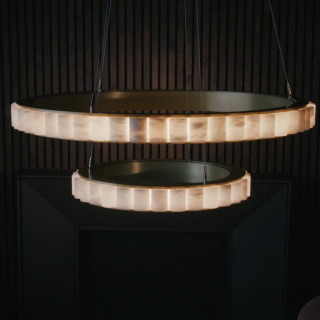 Close view of the two-tier alabaster chandelier lit against a dark slatted wood wall.