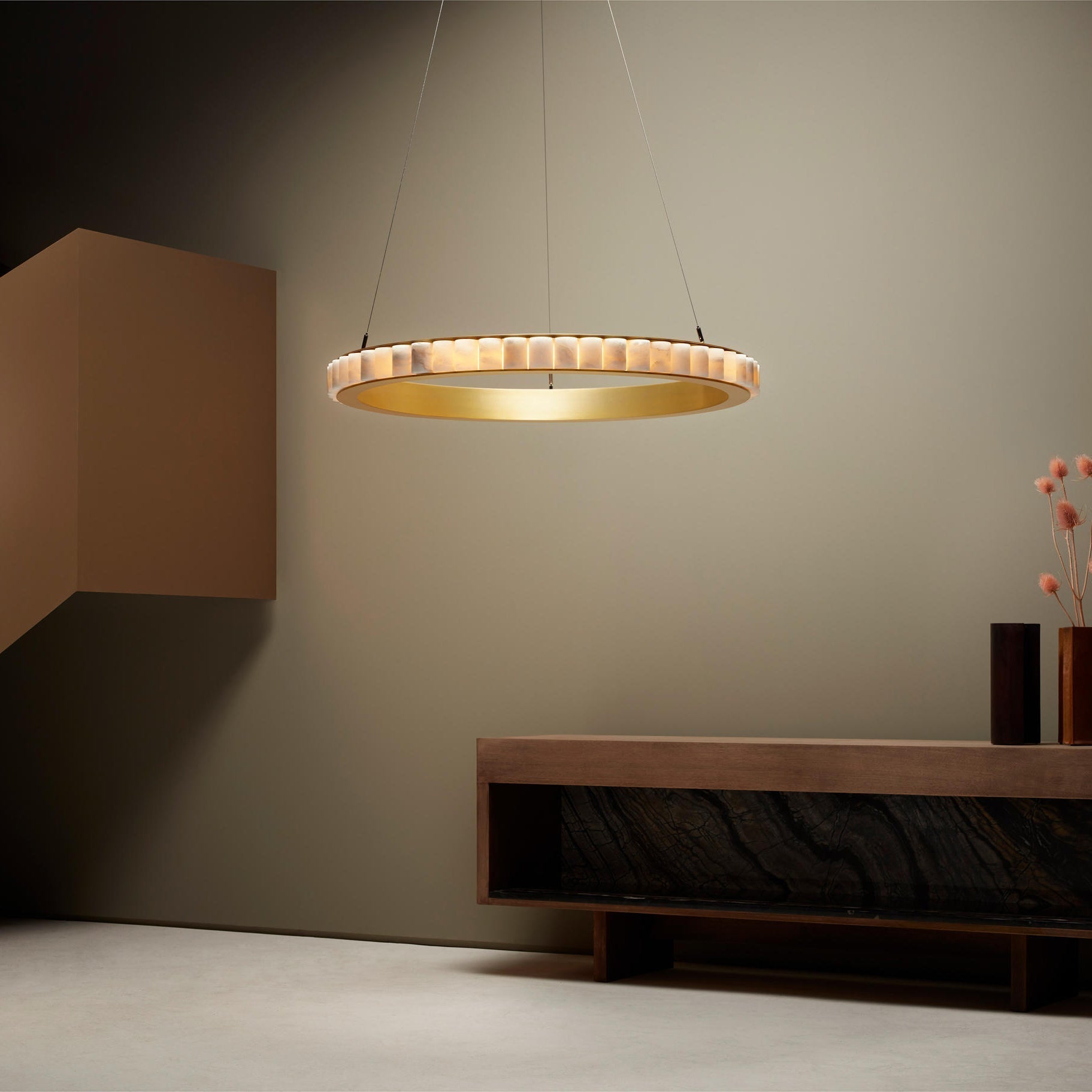 Brass alabaster chandelier lit beside a wall above a wooden console with a dark marble insert.