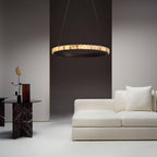 Dark bronze alabaster chandelier lit over a white sofa, stone tiles glowing in a dim living room.
