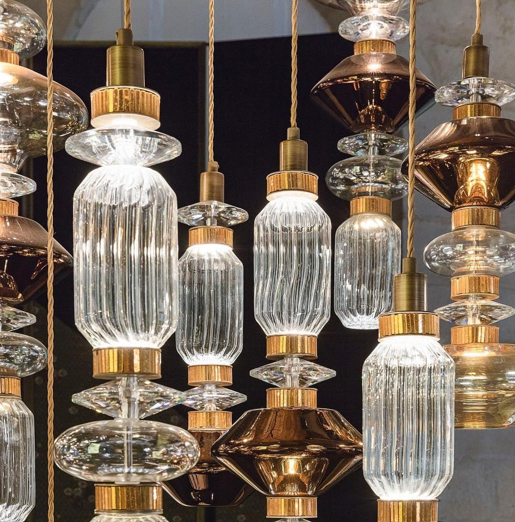Glass pendant light with gold cable hanging in a room