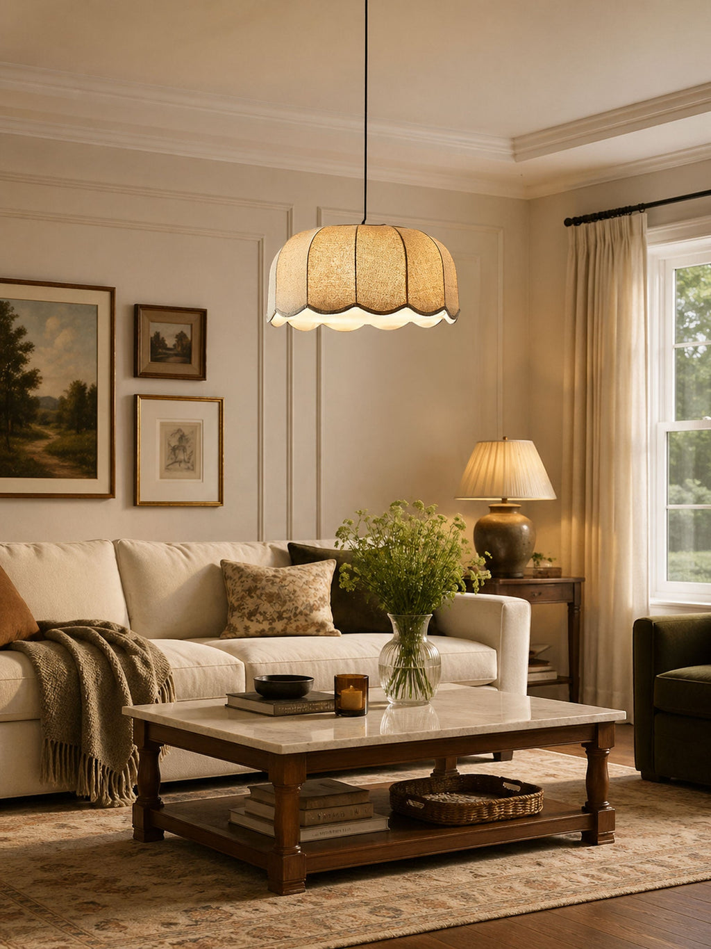 In a living room with a cream sofa and framed art, this beige Clérachic pendant lamp hangs above the coffee table.