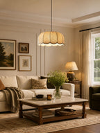 In a living room with a cream sofa and framed art, this beige Clérachic pendant lamp hangs above the coffee table.