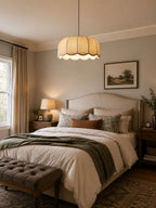 Near a framed landscape print in a softly lit bedroom, this beige Clérachic pendant lamp hangs from its cord.