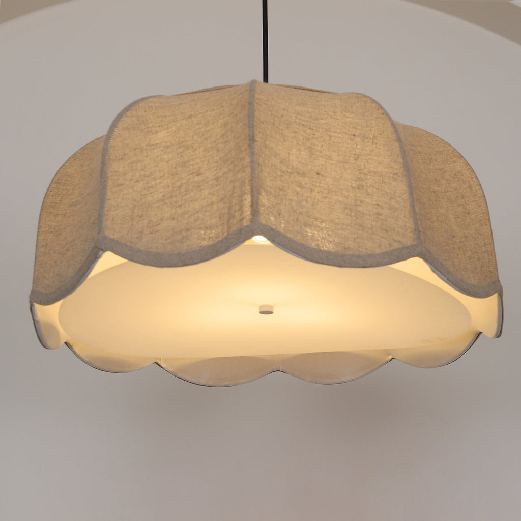 Seen from below, this beige Clérachic pendant lamp glows warmly, its scalloped edge fully visible around the shade.