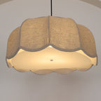 Seen from below, this beige Clérachic pendant lamp glows warmly, its scalloped edge fully visible around the shade.