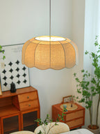 Beside a curtained window with a houseplant and patterned wall art, this beige Clérachic pendant lamp glows softly.
