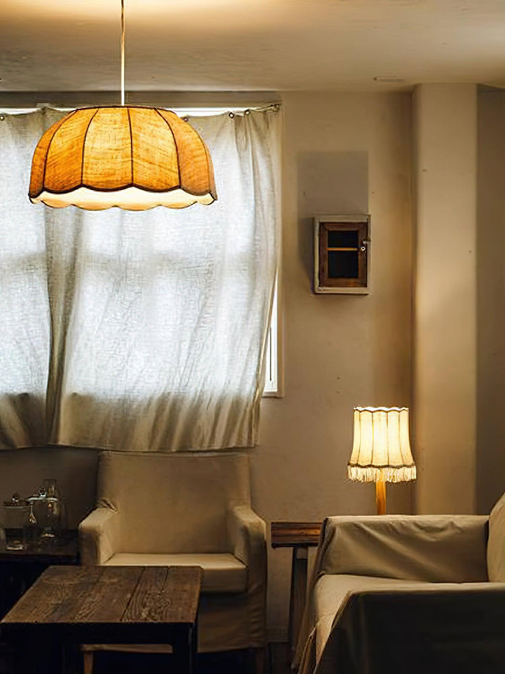 In a warmly toned room with armchairs and a floor lamp, this Clérachic pendant lamp glows above a curtained window.