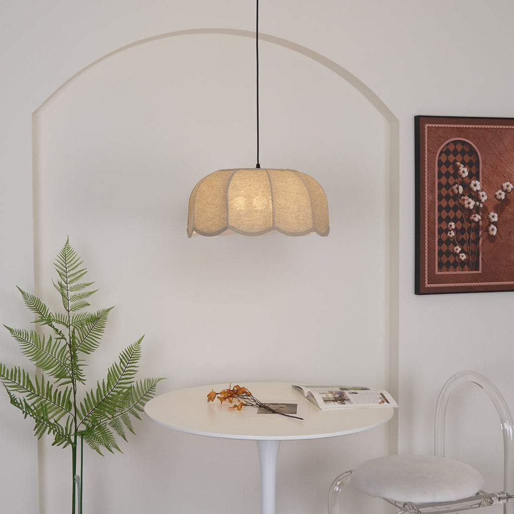 Close beneath a tall arch, this beige Clérachic pendant lamp lights a round table set with a fern sprig and magazine.