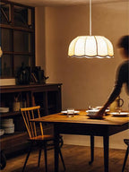 Someone sets out plates in a rustic kitchen beneath this lit beige Clérachic pendant lamp.