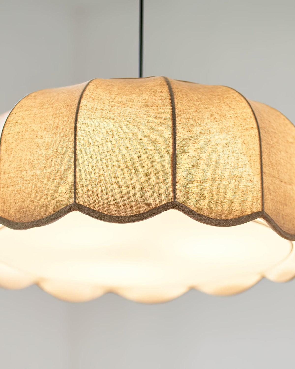 Close view of the scalloped shade's underside on this Clérachic pendant lamp, glowing white from within.