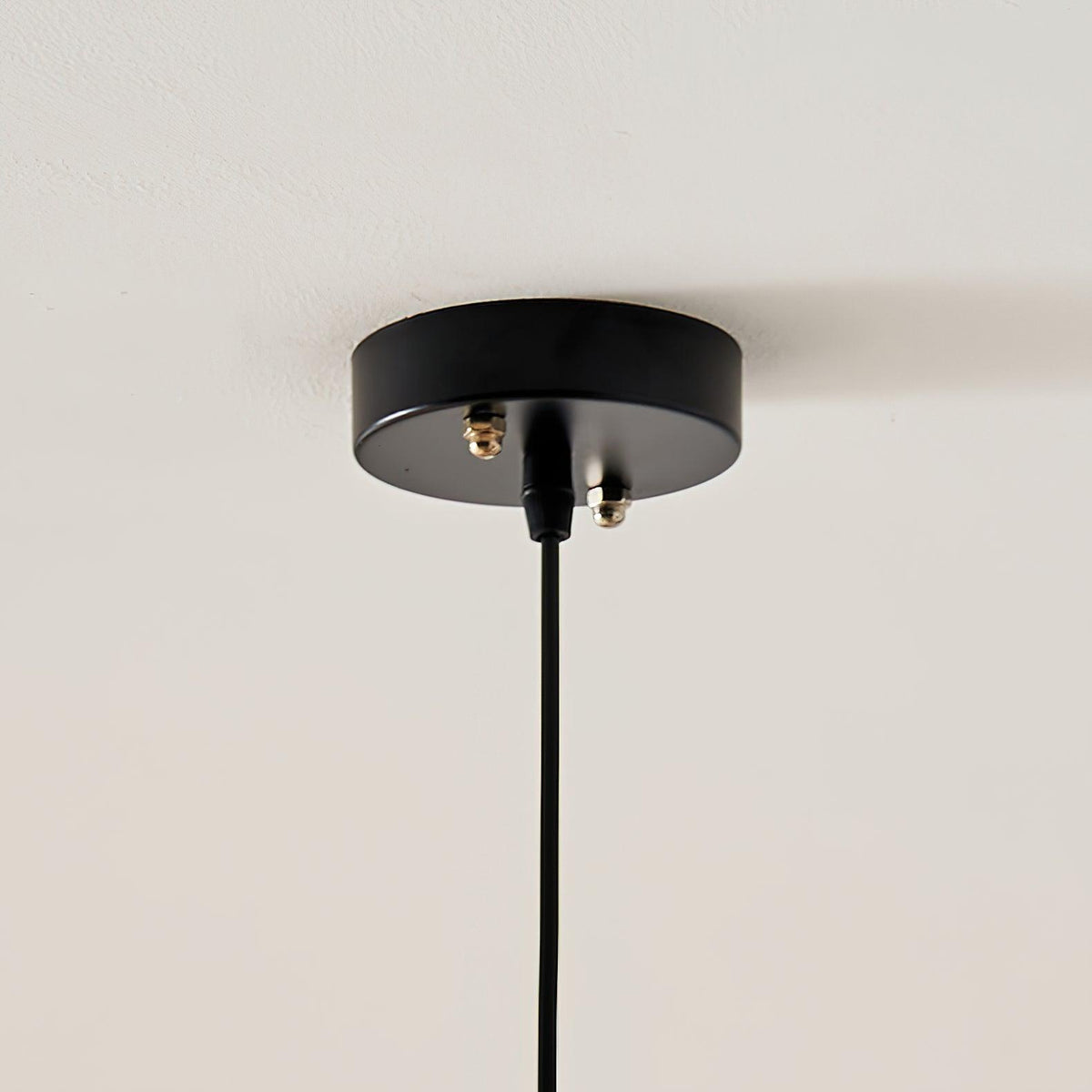 Close-up of the black ceiling canopy and cord fixing for this Clérachic pendant lamp.