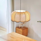 Lit and seen from below, this Clérachic pendant lamp's scalloped shade hangs above a small wooden cabinet.