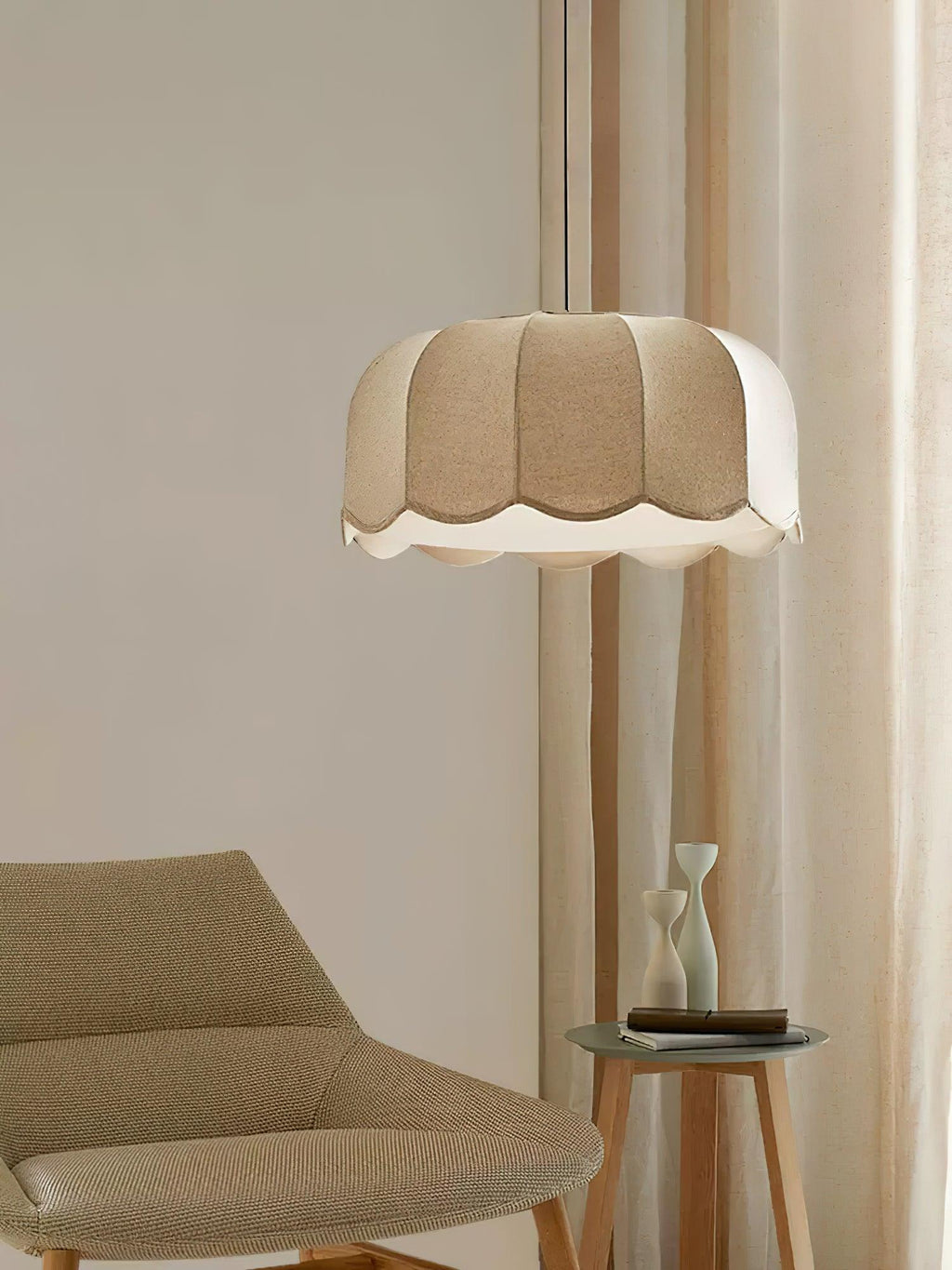 Near a beige armchair and a small round side table in sunlight, this beige Clérachic pendant lamp hangs from its cord.