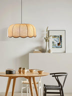 In a dining nook with a round wood table and mismatched chairs, this beige Clérachic pendant lamp hangs overhead.