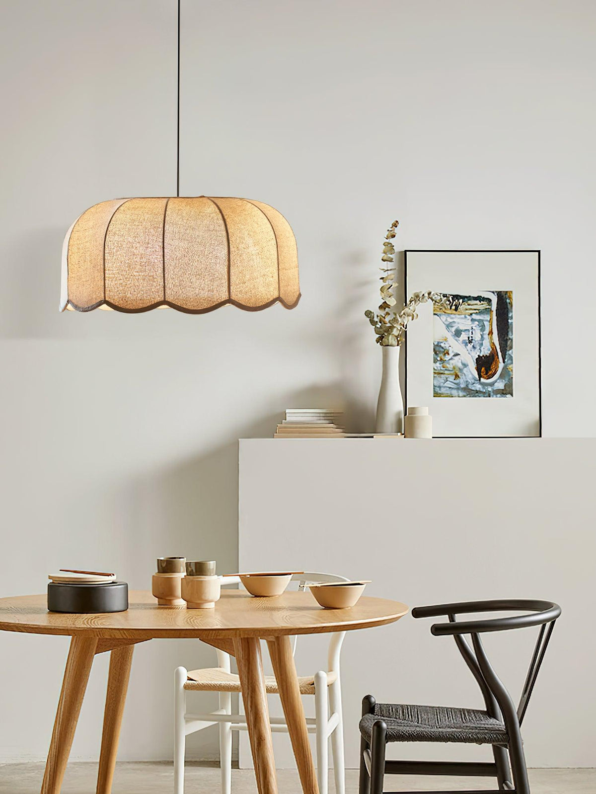 In a dining nook with a round wood table and mismatched chairs, this beige Clérachic pendant lamp hangs overhead.