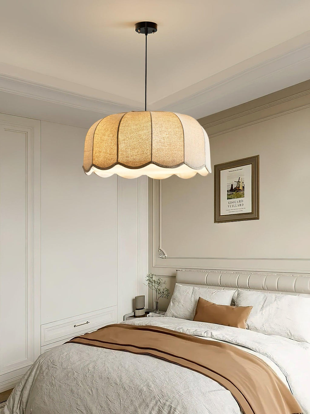 Above a bed with a striped throw in a moulded, panelled bedroom, this beige Clérachic pendant lamp hangs low.