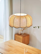 Close view of the scalloped fabric panels on this Clérachic pendant lamp, hanging above a wooden nightstand.