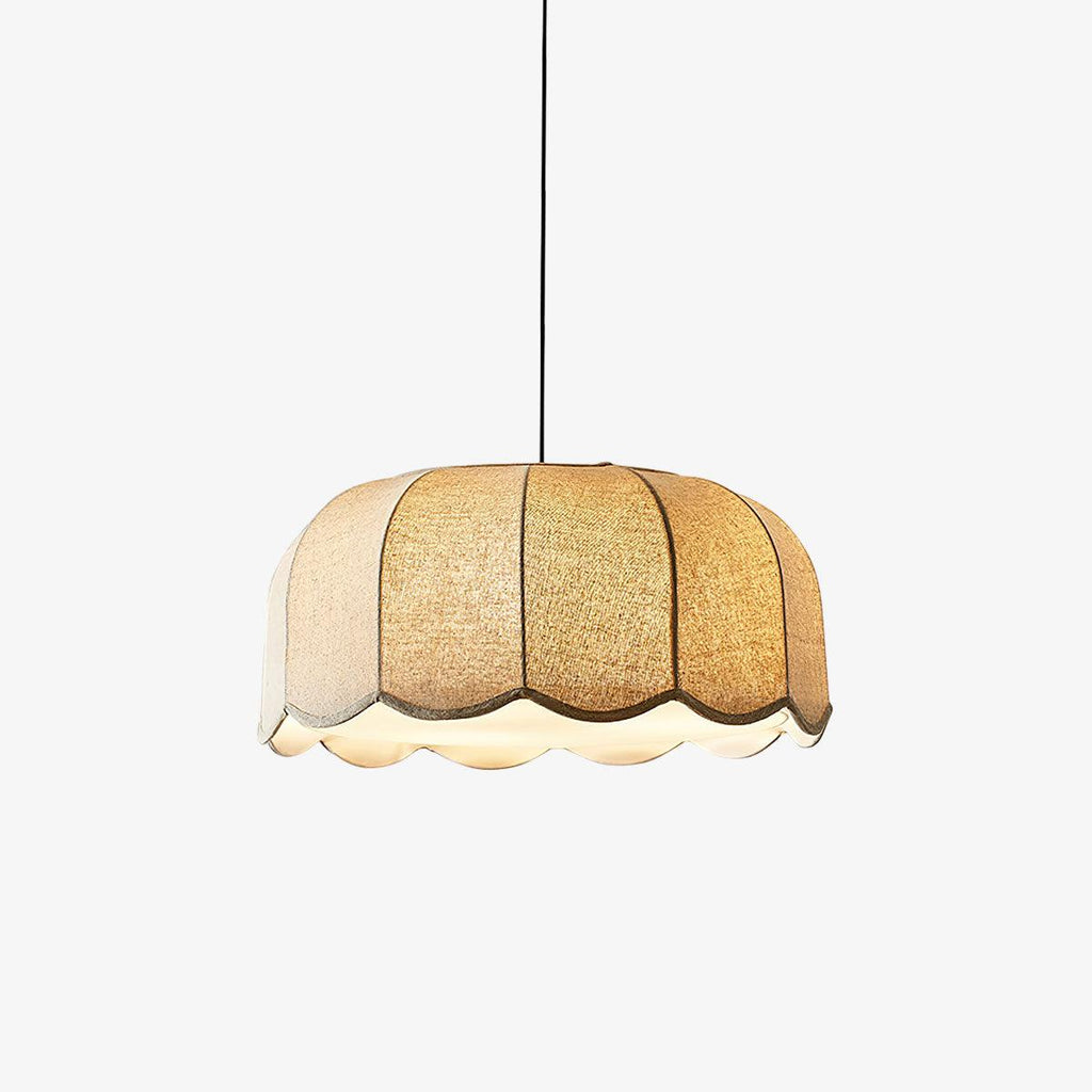 A beige Clérachic pendant lamp glows on a plain backdrop, its fabric petals fully lit.