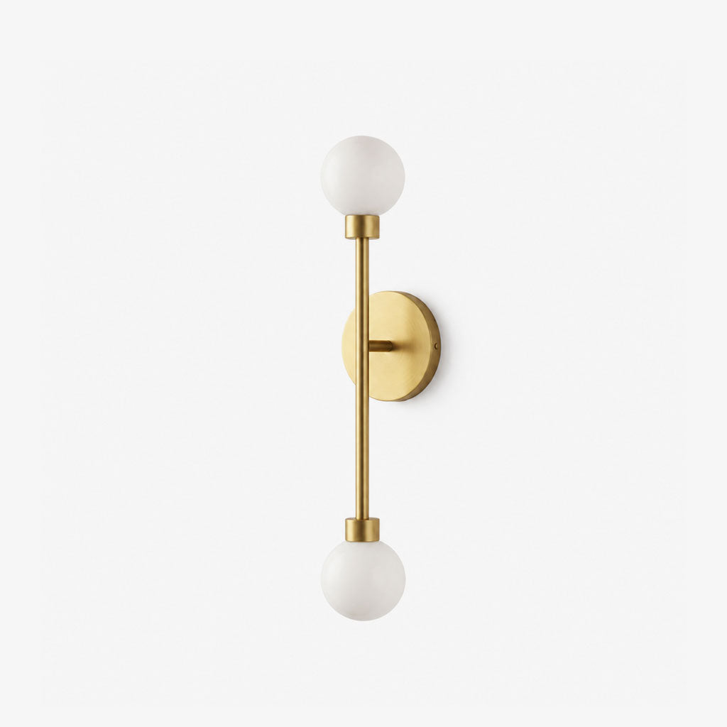 Studio shot of this Clérachic sconce in brass finish, its two alabaster ball shades capping a vertical rod.