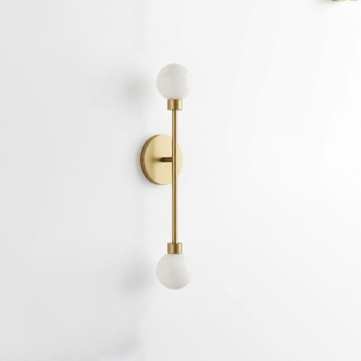 Close view of this Clérachic sconce in brass finish, showing the vertical rod between its two ball shades.