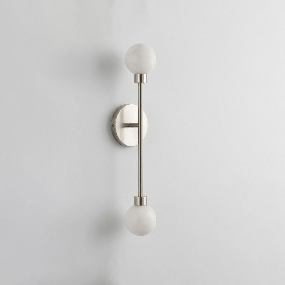 A front view of this Clérachic sconce in satin nickel finish, its two alabaster ball shades on a vertical rod.