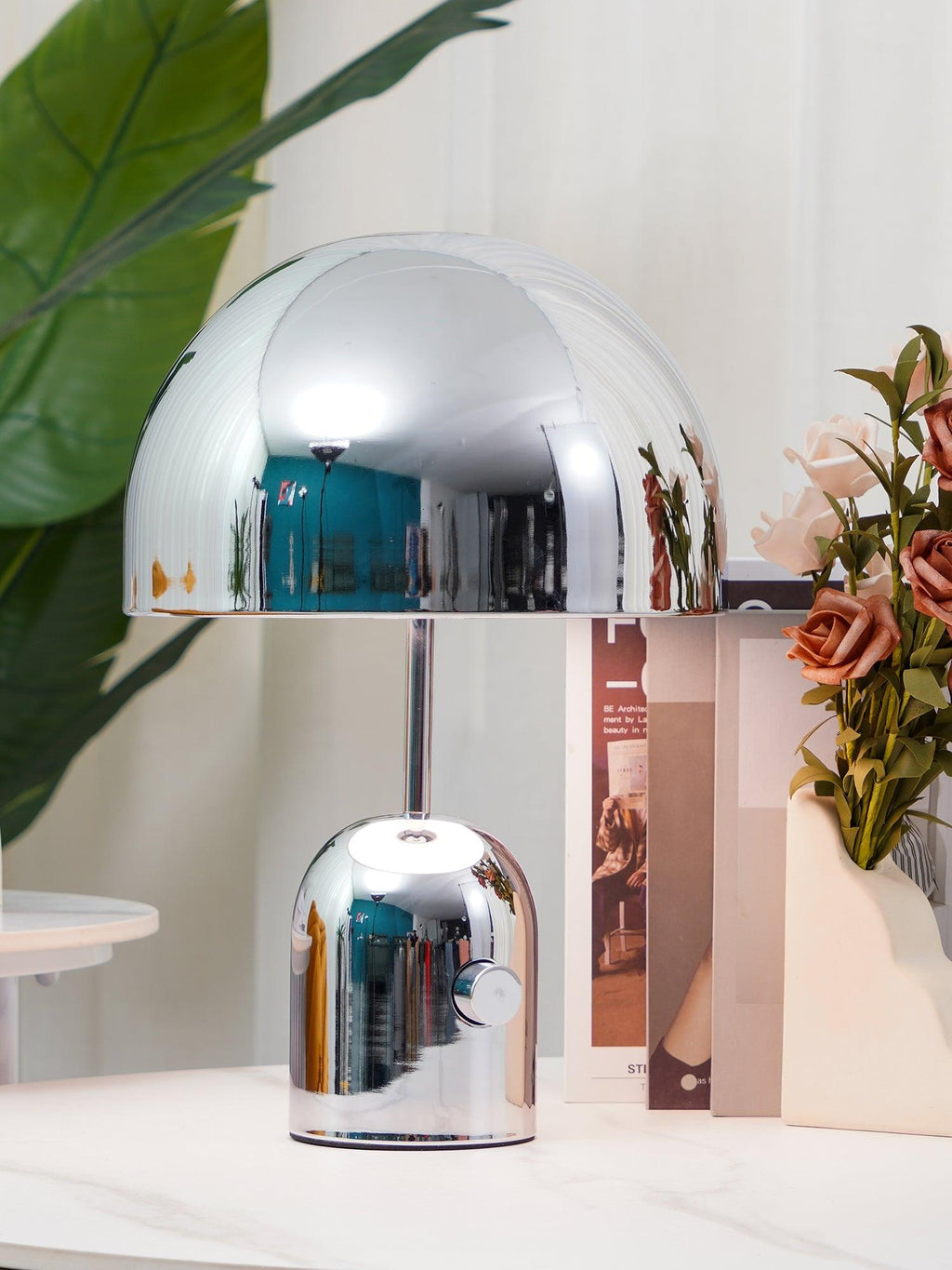 A tall chrome dome lamp and a shorter matching one from Clérachic stand on a marble surface beside pink flowers.