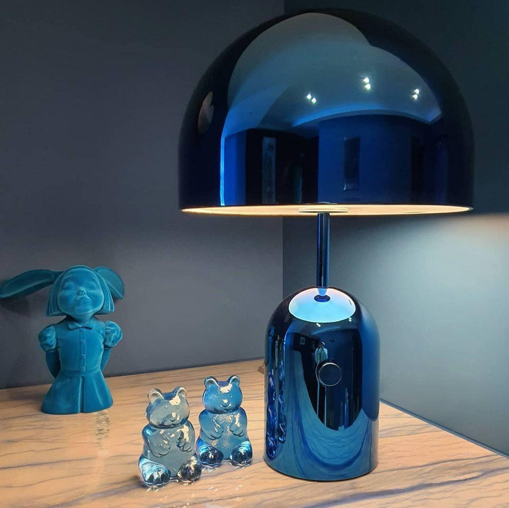 In blue, this Clérachic table lamp stands on a wood table beside small teal figurines of owls and a girl.