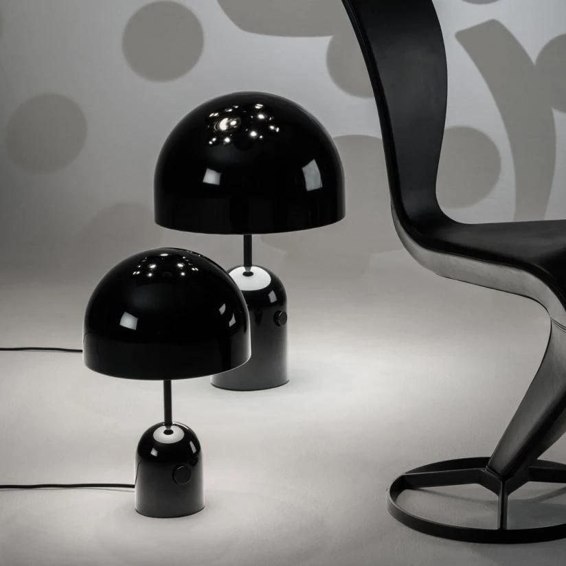 This Clérachic table lamp appears in black beside a smaller matching lamp, both on white near a sculptural chair.