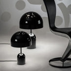 This Clérachic table lamp appears in black beside a smaller matching lamp, both on white near a sculptural chair.
