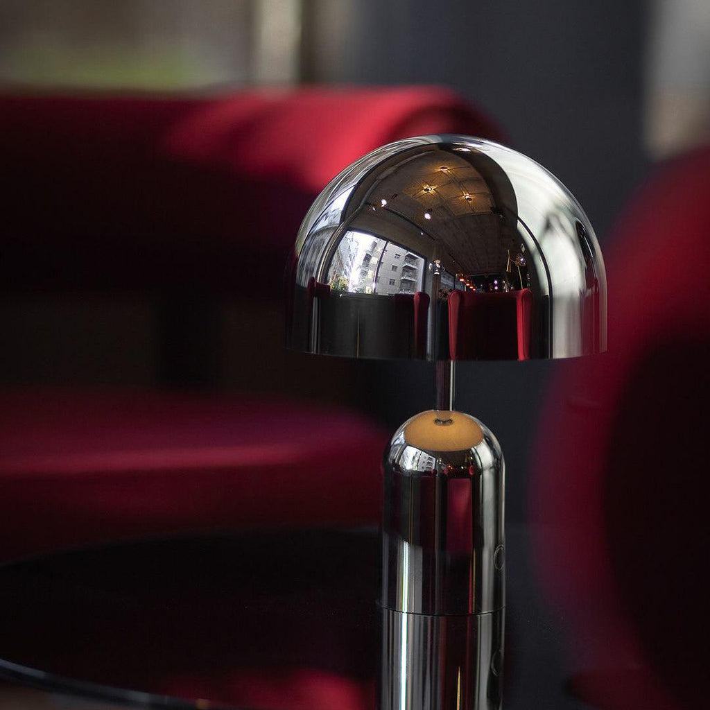 A close-up against deep red velvet shows the dome shade and stem of this Clérachic chrome table lamp.