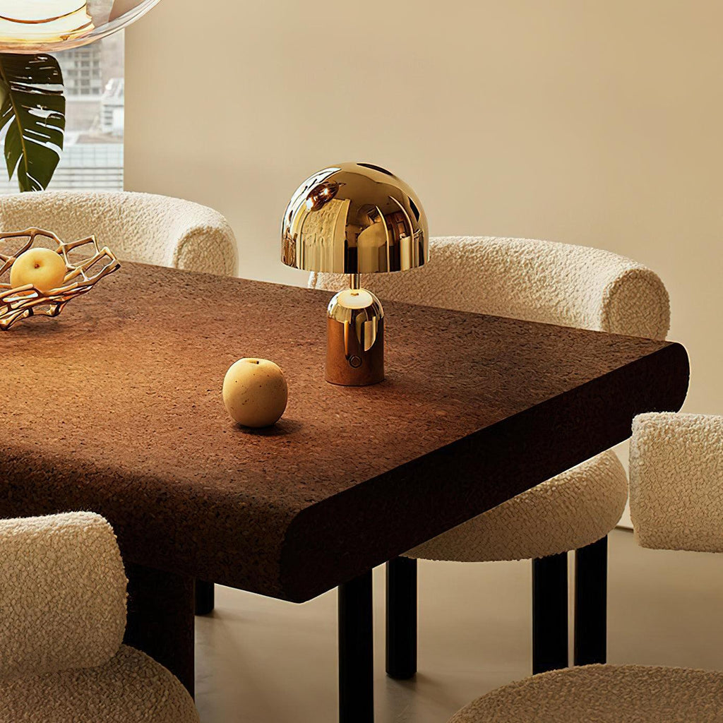 Two sizes of this Clérachic table lamp in gold stand on a dark wood dining table beside a single pear.