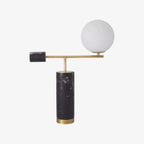 A Clérachic desk lamp with a black marble base and counterweight sits on white, its glass globe shown unlit.