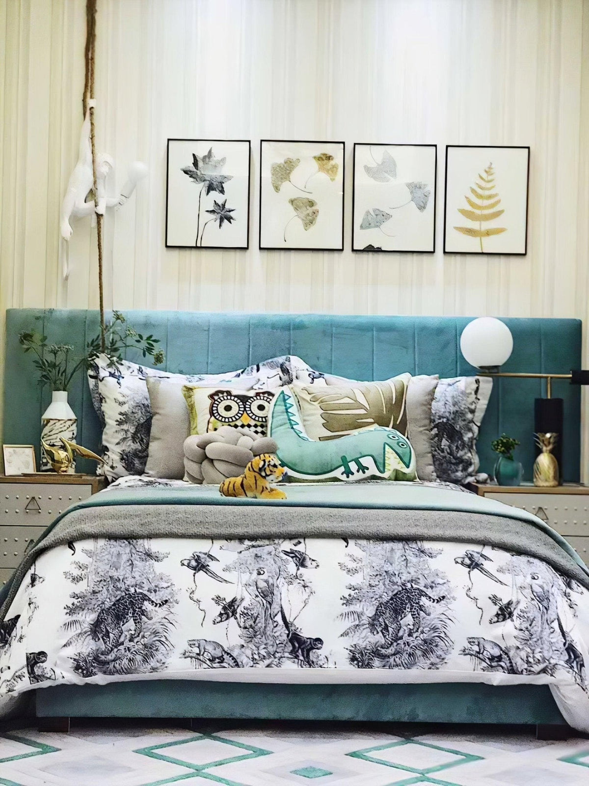 Seen across a bedroom with a teal upholstered headboard and framed leaf prints, the Clérachic desk lamp glows softly on the nightstand.