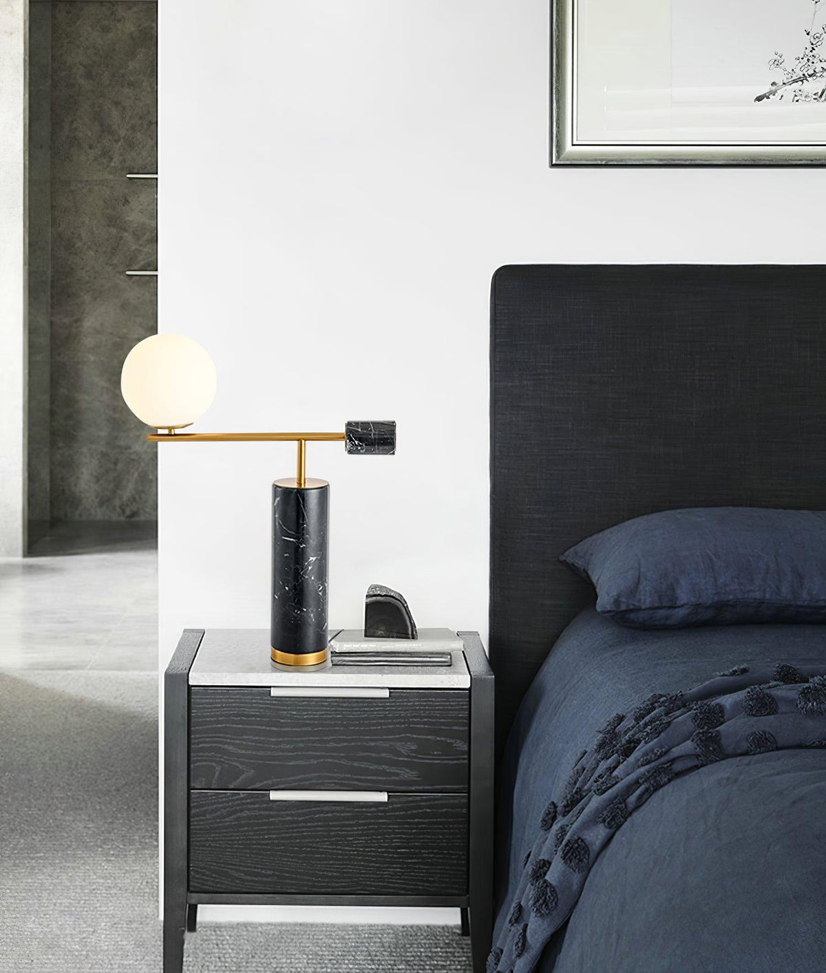 A Clérachic desk lamp glows on a grey nightstand beside a dark upholstered headboard and a phone left charging.