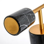 Close-up of the Clérachic desk lamp's black marble counterweight, its gold end cap catching the light against the veining.