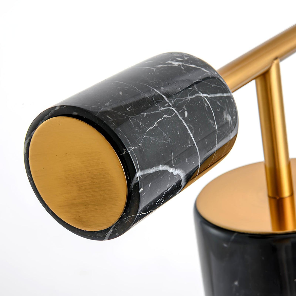 Close-up of the Clérachic desk lamp's black marble counterweight, its gold end cap catching the light against the veining.