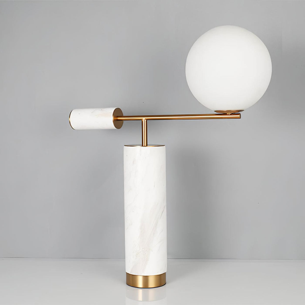 This Clérachic desk lamp in the white marble finish stands against a plain grey backdrop, its glass globe unlit.