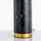Close-up of the Clérachic desk lamp's black marble base and its gold ring foot, with the power cord visible on the floor.