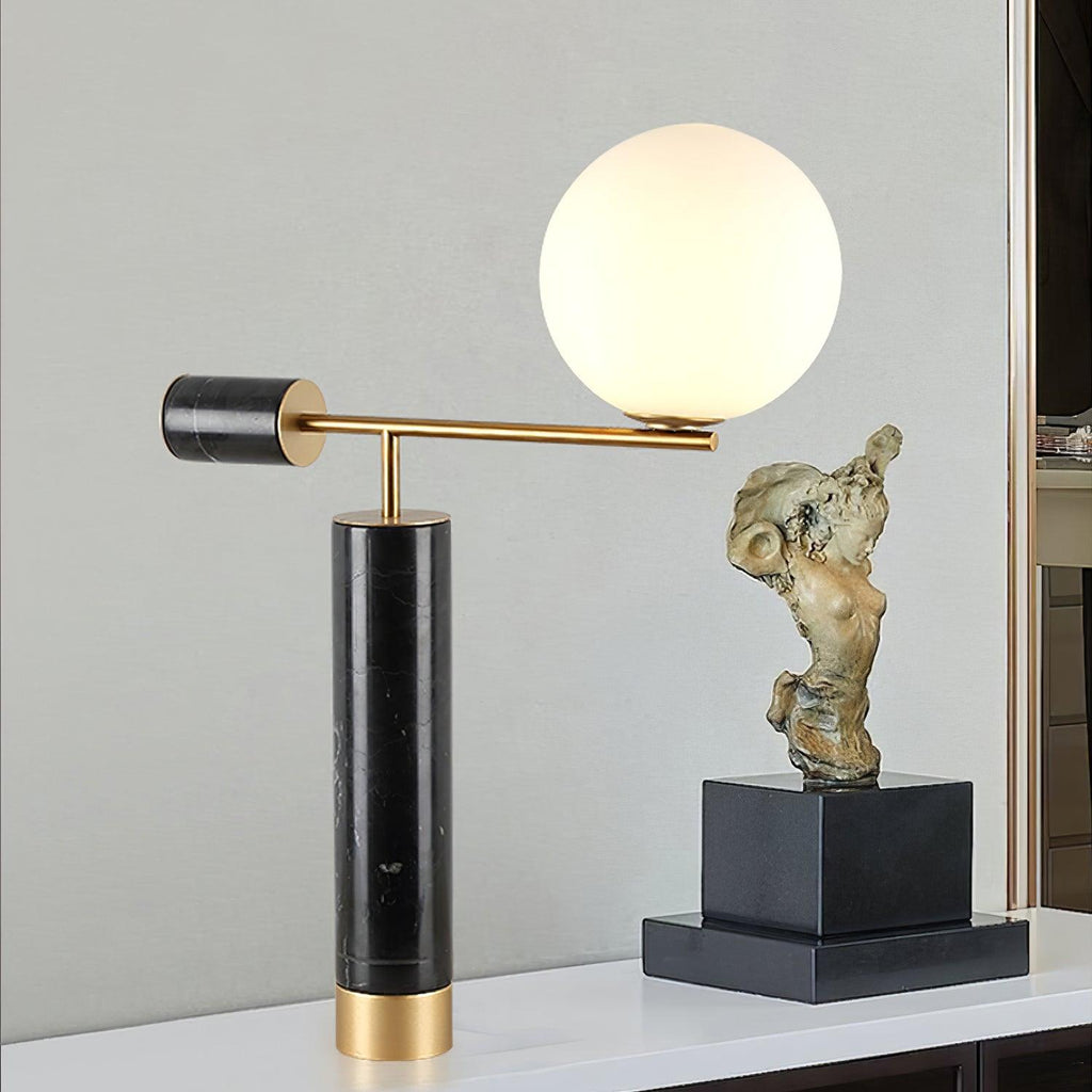 A Clérachic desk lamp with a black marble base stands on a console beside a bronze figure sculpture and dark plinth.