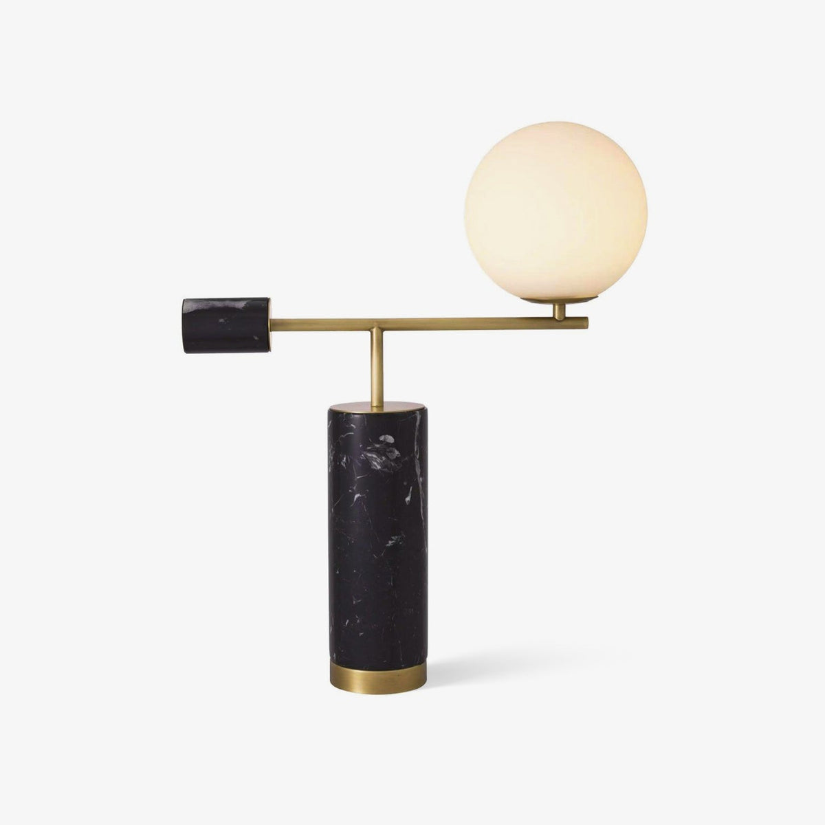 Clérachic desk lamp on a white background, its lit glass globe glowing warm above a black marble base and gold arm.