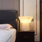 The same bedside scene from a slightly wider angle, showing more of the black tufted headboard by the Clérachic lamp.