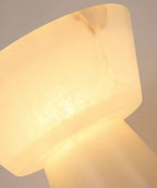 Close-up of the Clérachic lamp's alabaster shade seam from another side, its grey veining glowing under the bulb.